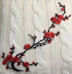 an embroidered piece with red flowers on it