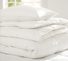 a stack of white pillows sitting on top of a bed