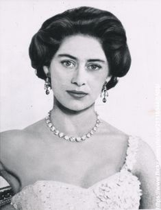 an old black and white photo of a woman in a dress with pearls on her neck