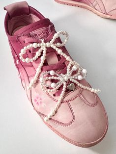 a pair of pink shoes with pearls on the laces and beads attached to them