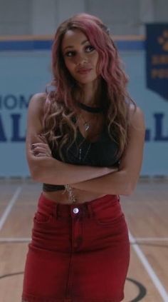 a woman standing in a gym with her arms crossed and looking at the camera while wearing a black crop top