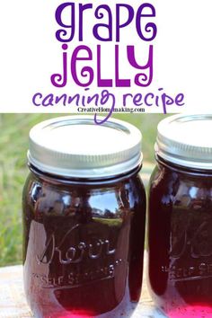 two mason jars filled with purple jelly sitting on top of a wooden table next to grass