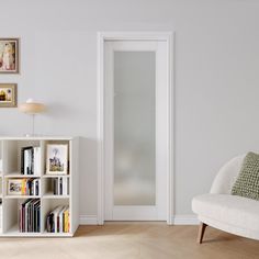 a living room with white furniture and pictures on the wall above it's bookshelf