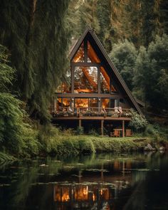 a house with a lake in front of it and trees around the outside, surrounded by greenery