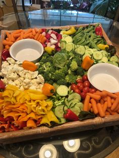 a platter filled with vegetables and dips on top of a glass countertop