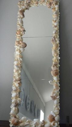 a mirror with seashells hanging on the side and an ocean themed frame around it