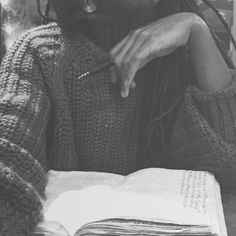 a black and white photo of a woman with dreadlocks sitting at a table