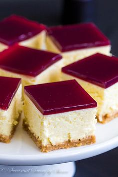 several pieces of cheesecake on a white plate with raspberry sauce in the middle