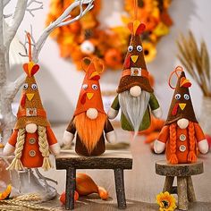 four gnomes are sitting on small benches in front of a wreath and pumpkin tree