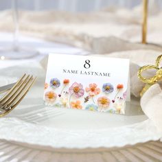 a place card is sitting on a plate with gold forks and napkins next to it