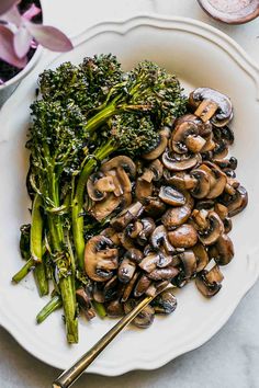 a white plate topped with mushrooms and broccoli