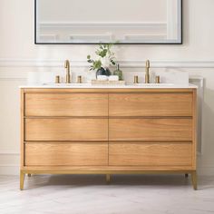 a bathroom vanity with two sinks and a large mirror on the wall above it in a white room