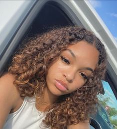 a woman with curly hair sitting in a car