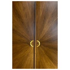 two wooden doors with gold handles on each side and one door has a circular handle in the middle