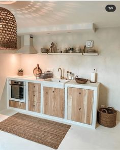 a kitchen with white walls and wooden cabinetry next to a rug on the floor