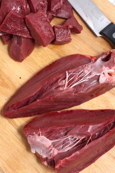 two pieces of raw meat on a cutting board next to a knife