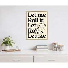 a white table with some books on it and a plant in the corner next to it