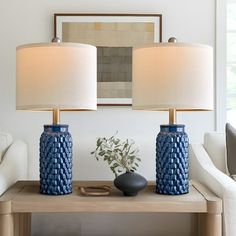 two blue vases sitting on top of a wooden table next to a white couch