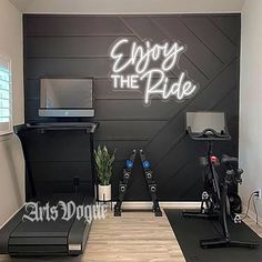 a gym room with exercise equipment in the corner and enjoy the ride written on the wall