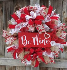 a wreath that says be mine with hearts and bows on the front, attached to a wooden fence