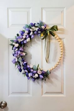 a wreath is hanging on the front door with flowers and pearls around it, as well as an egg shell bead necklace