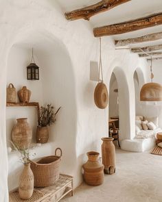 a room filled with lots of vases and baskets on top of wooden shelves next to white walls