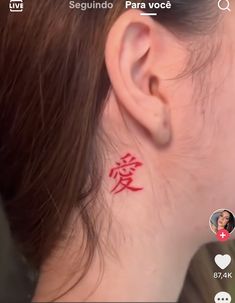 a woman's ear with a red tattoo on it