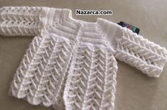 a white knitted sweater sitting on top of a floor next to a tag with the name nazcar com