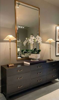 a large mirror sitting on top of a dresser next to a vase with flowers in it