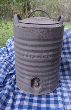 an old metal container sitting on top of a blue and white checkered table cloth