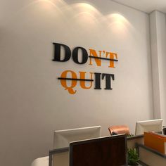 an office with white walls and orange letters on the wall that says don't quit