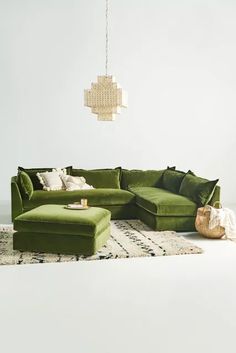 a living room with green couches and rugs on the floor in front of a chandelier