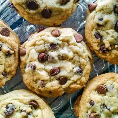 several chocolate chip cookies sitting on top of a glass plate with one cookie in the middle