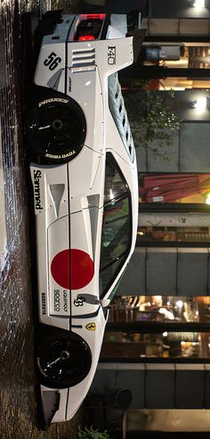 a white race car hanging from the side of a building