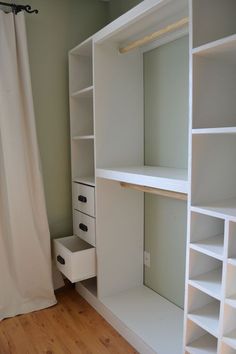 a white closet with shelves and drawers next to a shower curtain in a room that has wood floors