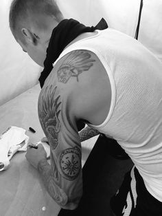 a man with a tattoo on his arm is sitting at a table and working on something