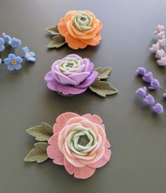 four different colored flowers on a black surface