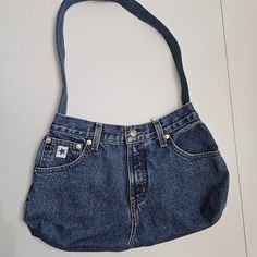 an old pair of blue jean shorts hanging from a purse on a white wall,