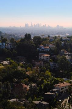 the city skyline is seen in this view from atop a hill with houses and trees