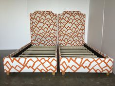 an orange and white bed frame with two matching headboards on each side, in front of a white wall