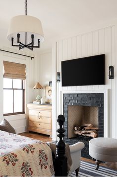 a bedroom with a bed, fireplace and television on the wall next to a window