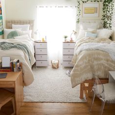 two beds in a bedroom with white carpet and plants on the windowsills above them