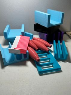 several pieces of blue and pink plastic on a white counter top, with one red object in the middle