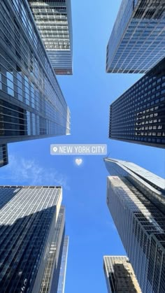 looking up at skyscrapers with the new york city sign in between them on a sunny day