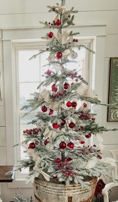 a white christmas tree with red ornaments in a basket