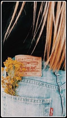 a yellow flower sticking out of the back pocket of someone's jeans