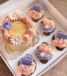 cupcakes decorated in pastel colors with flowers and ribbons are on a tray