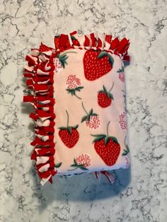 a red and white cloth with strawberries on it sitting on a marble counter top