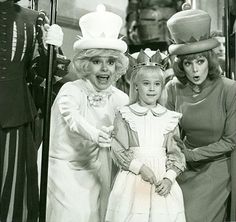 three women standing next to each other with hats on top of their heads and dresses