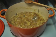 a pot filled with food sitting on top of a stove next to a wooden spoon